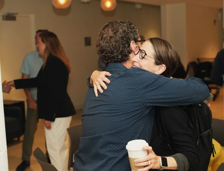 Two attendees hugging hello at the Chicago Bagel Bash