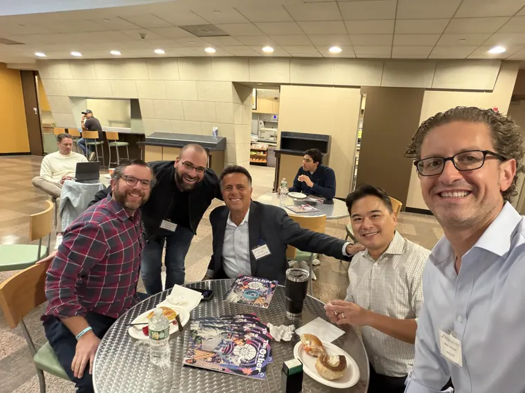 Jordan Isenstadt with guests around a table with coffee and bagels at the Long Island Bagel Bash